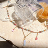 Clear glass with intricate designs on a textured surface with a beaded necklace.