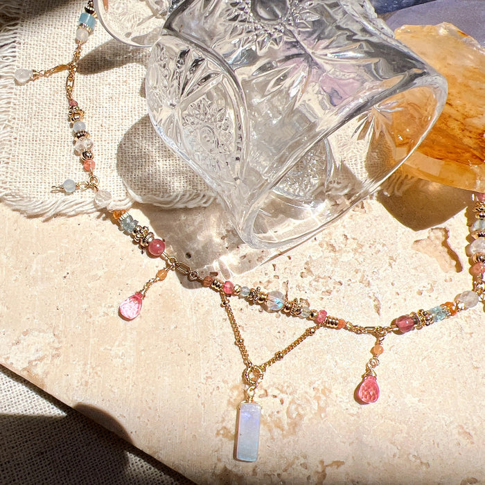 Clear glass with intricate designs on a textured surface with a beaded necklace.